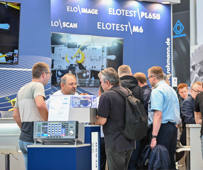 A group of men are standing around a display of elotest products