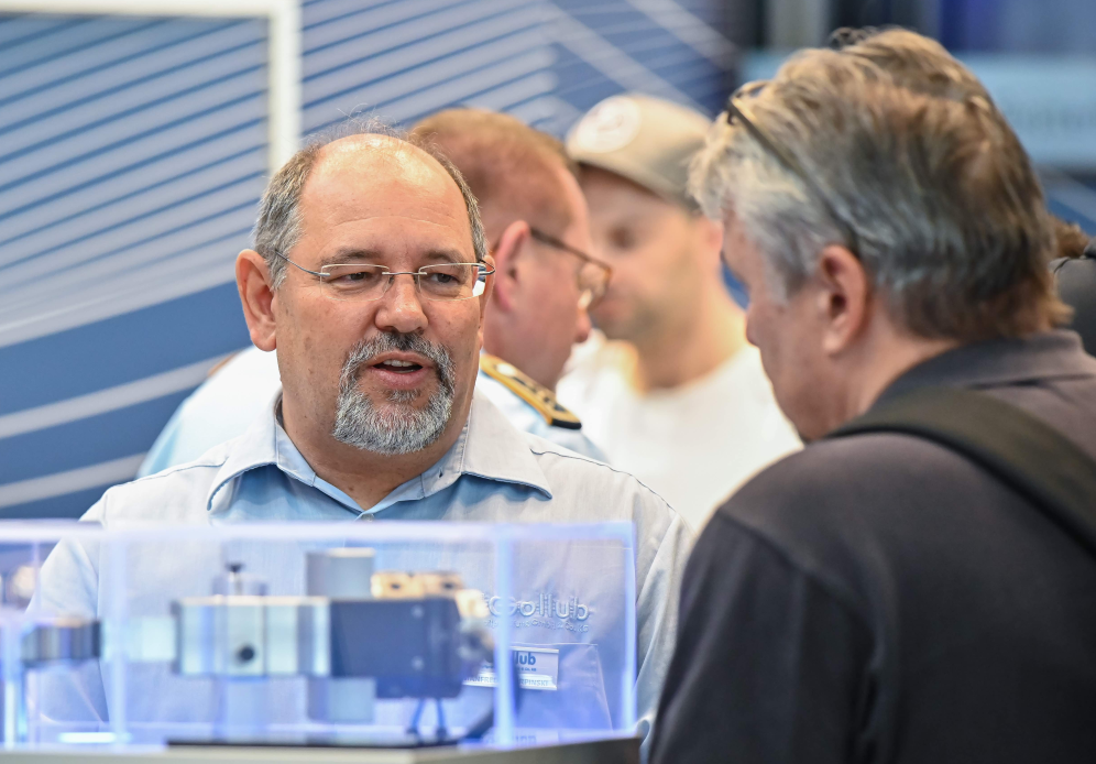 A group of men are standing around a table talking to each other.