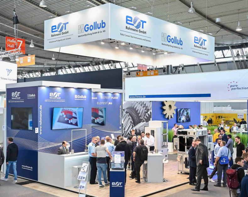 A group of people are standing around a booth at a trade show