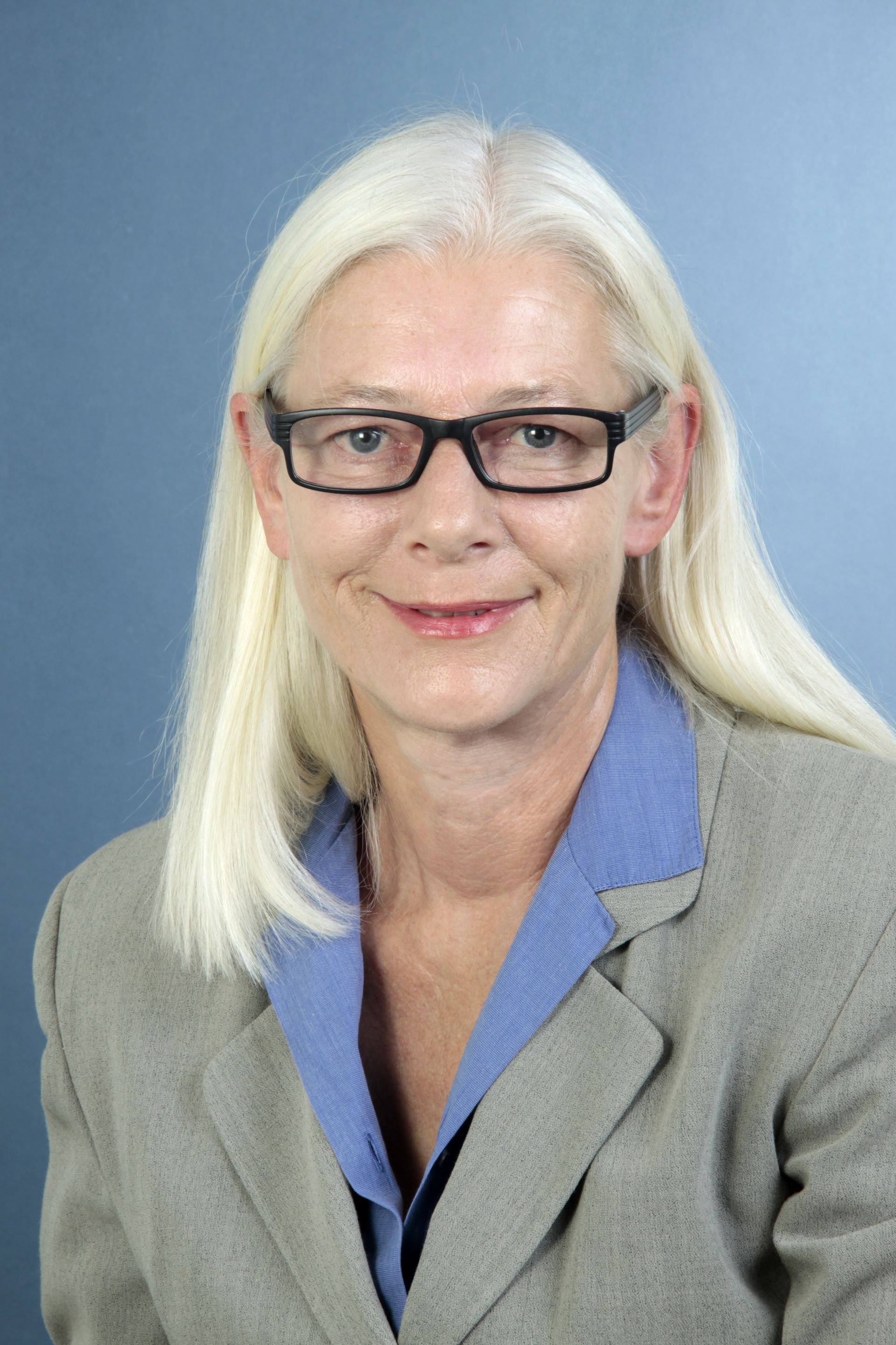 A woman in a suit stands in front of a bouquet of flowers