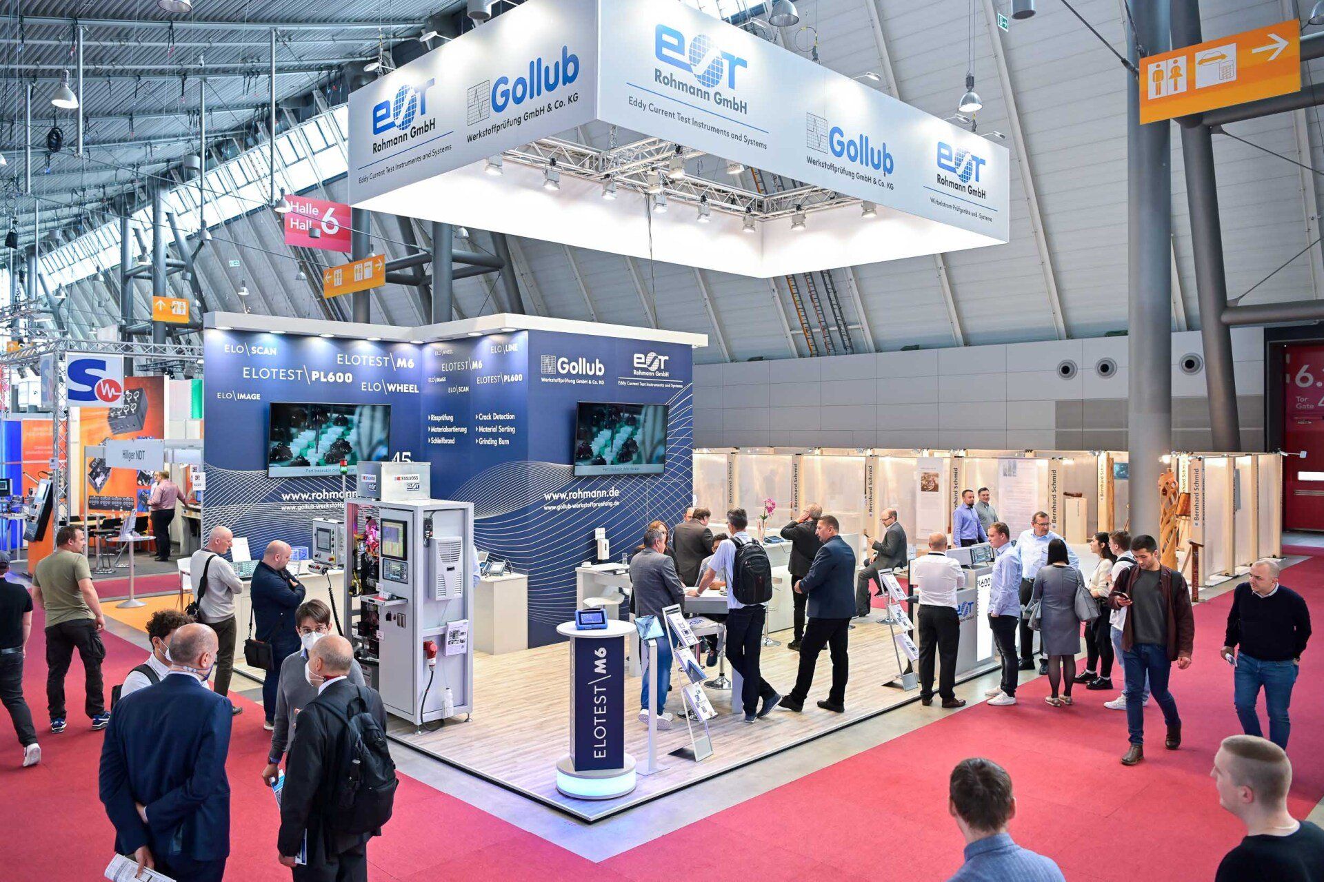 A group of people are standing around a booth at a convention.