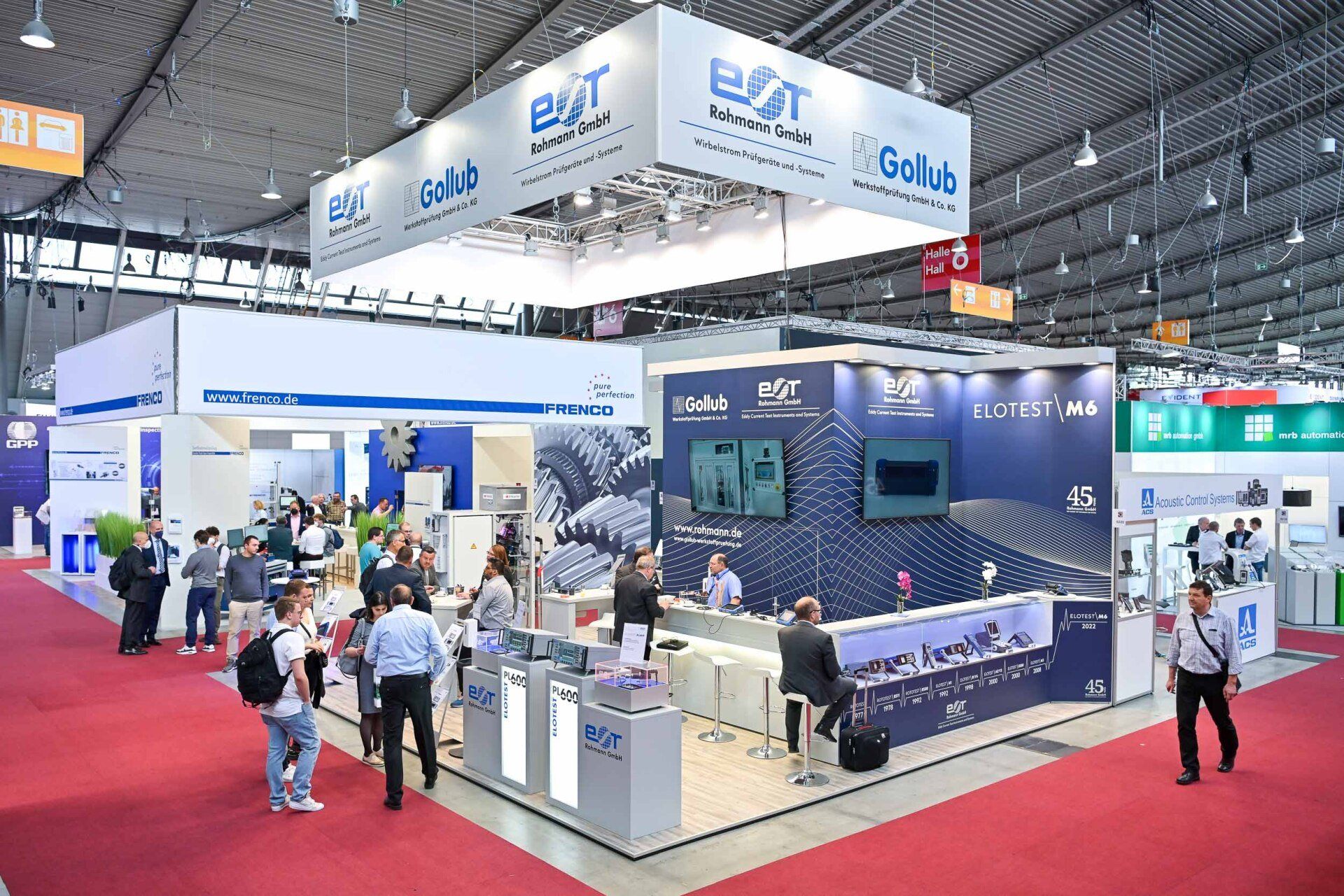 A group of people are standing around a booth at a convention.