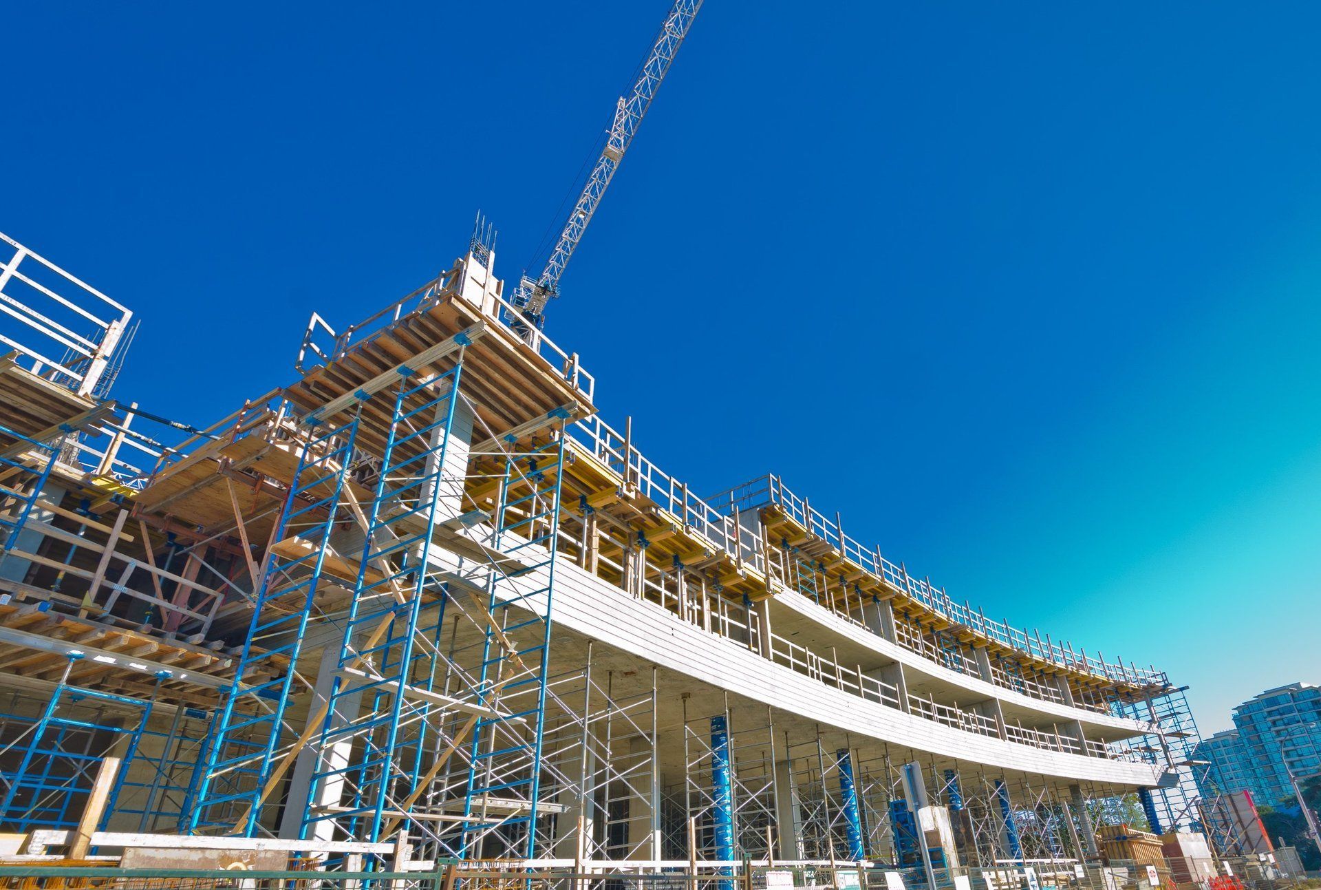 A large building is being built with scaffolding and a crane.
