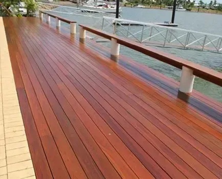 A Wooden Deck With a Railing Overlooking a Body of Water — Timbertop Floor Sanding & Polishing In Bungalow, QLD
