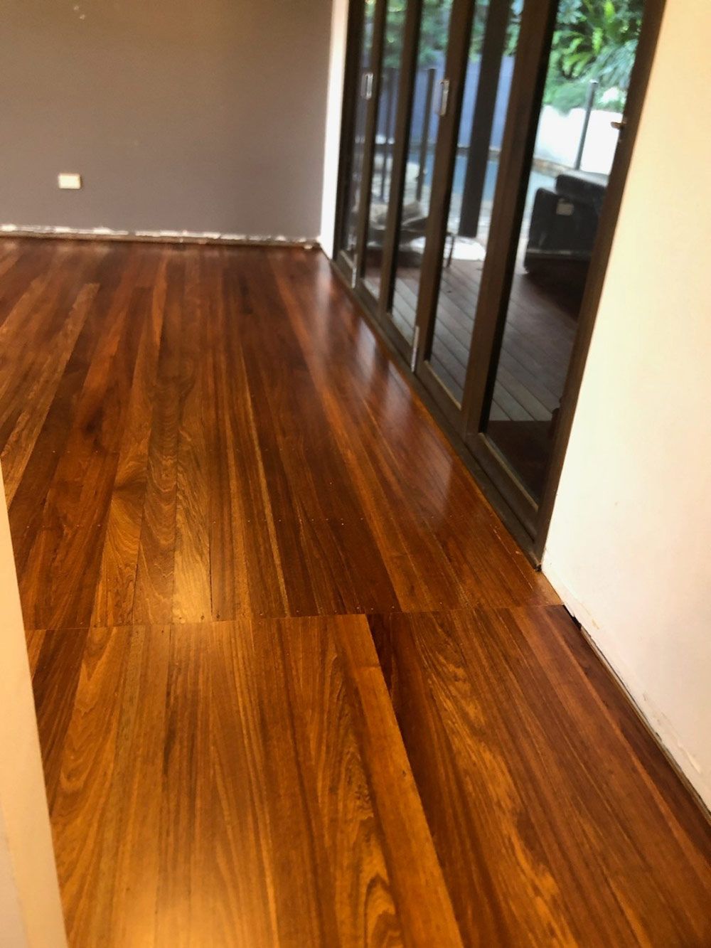 A Room With Hardwood Floors and Sliding Glass Doors — Timbertop Floor Sanding & Polishing In Port Douglas, QLD