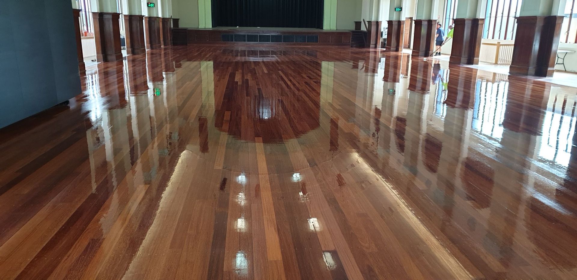 Shiny Wooden Floor Reflecting The Room With Pillars And A Stage — Timbertop Floor Sanding & Polishing In Port Douglas, QLD