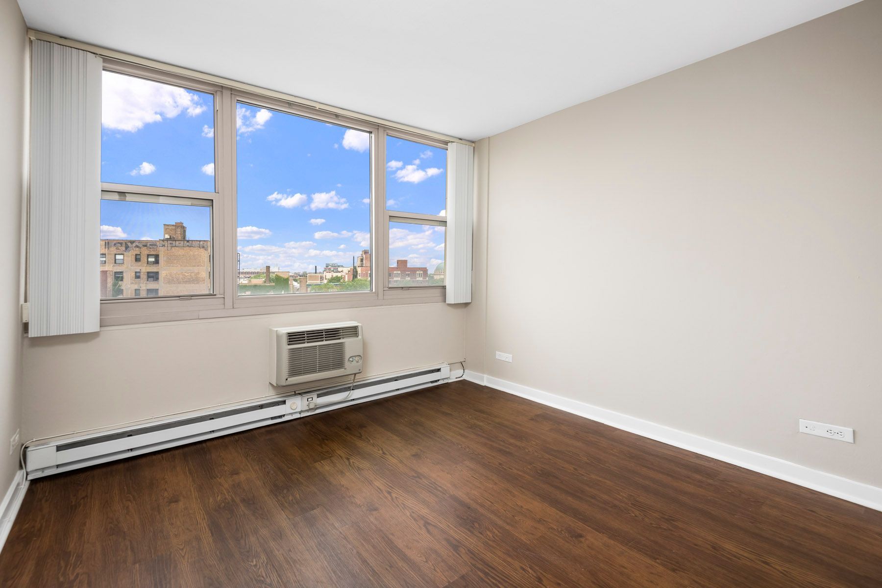 An empty room with hardwood floors and a large window at Park Lincoln by Reside.
