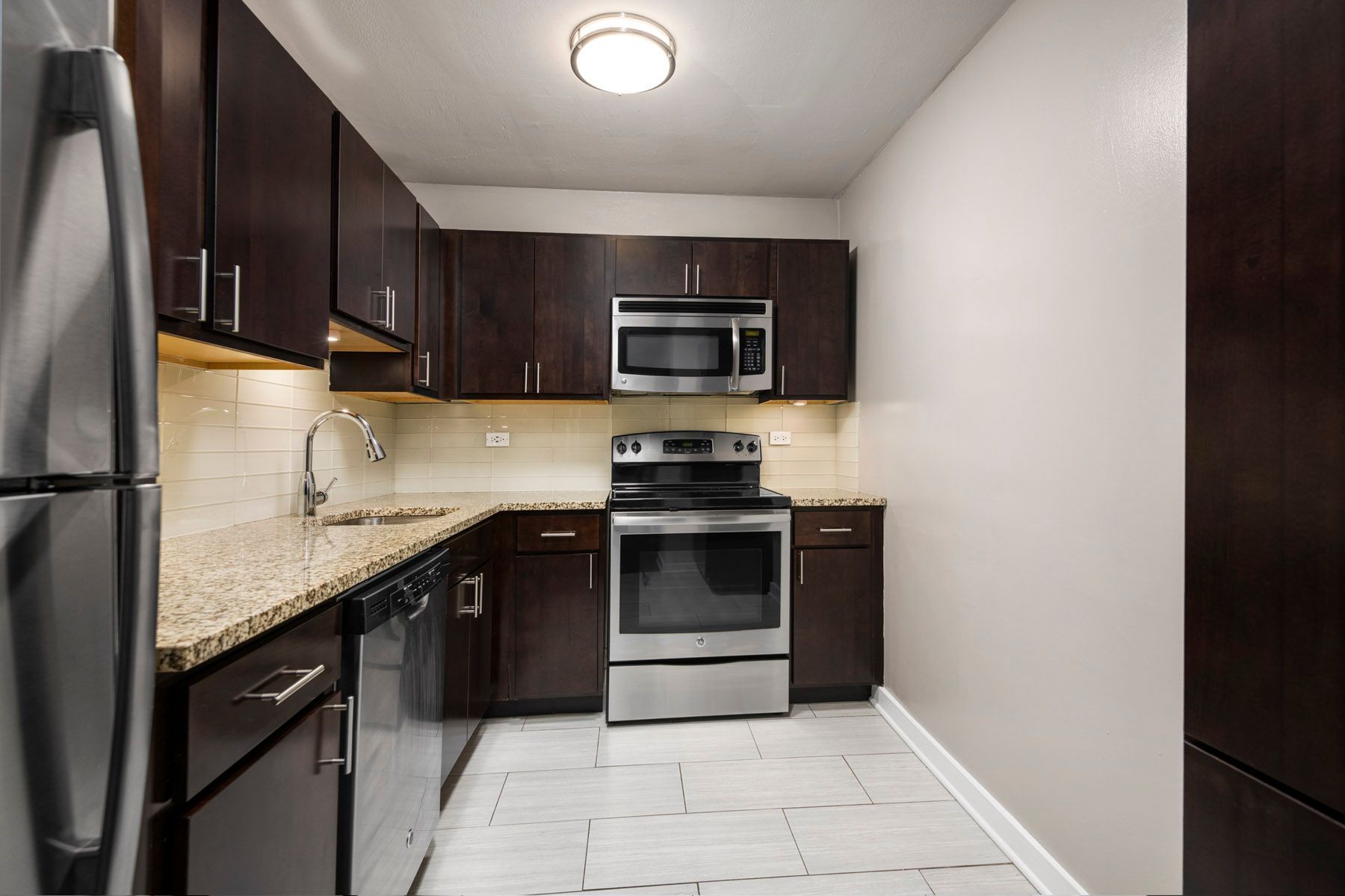 A kitchen with stainless steel appliances and brown cabinets at Park Lincoln by Reside.