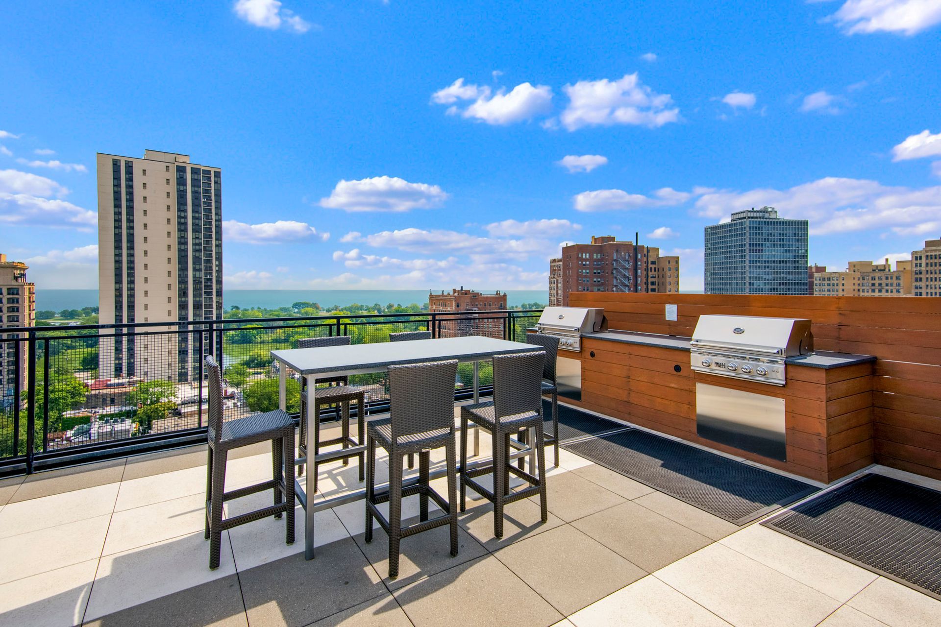 A rooftop patio with a table and chairs and a grill at Park Lincoln by Reside.
