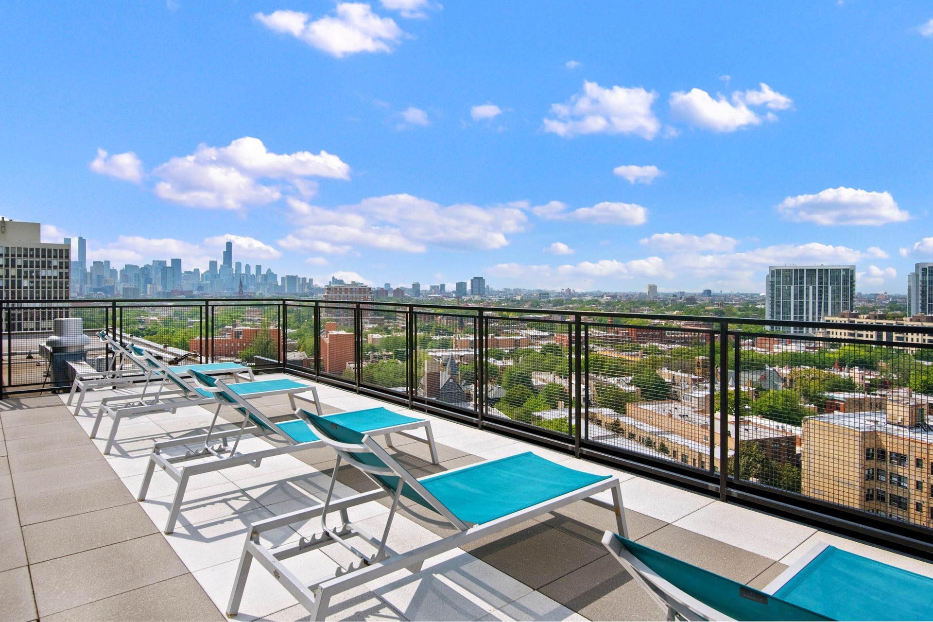A row of blue lounge chairs on a balcony overlooking a city at Park Lincoln by Reside.