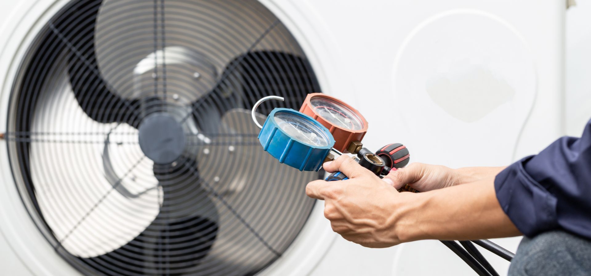 A man is holding two gauges in front of a fan.