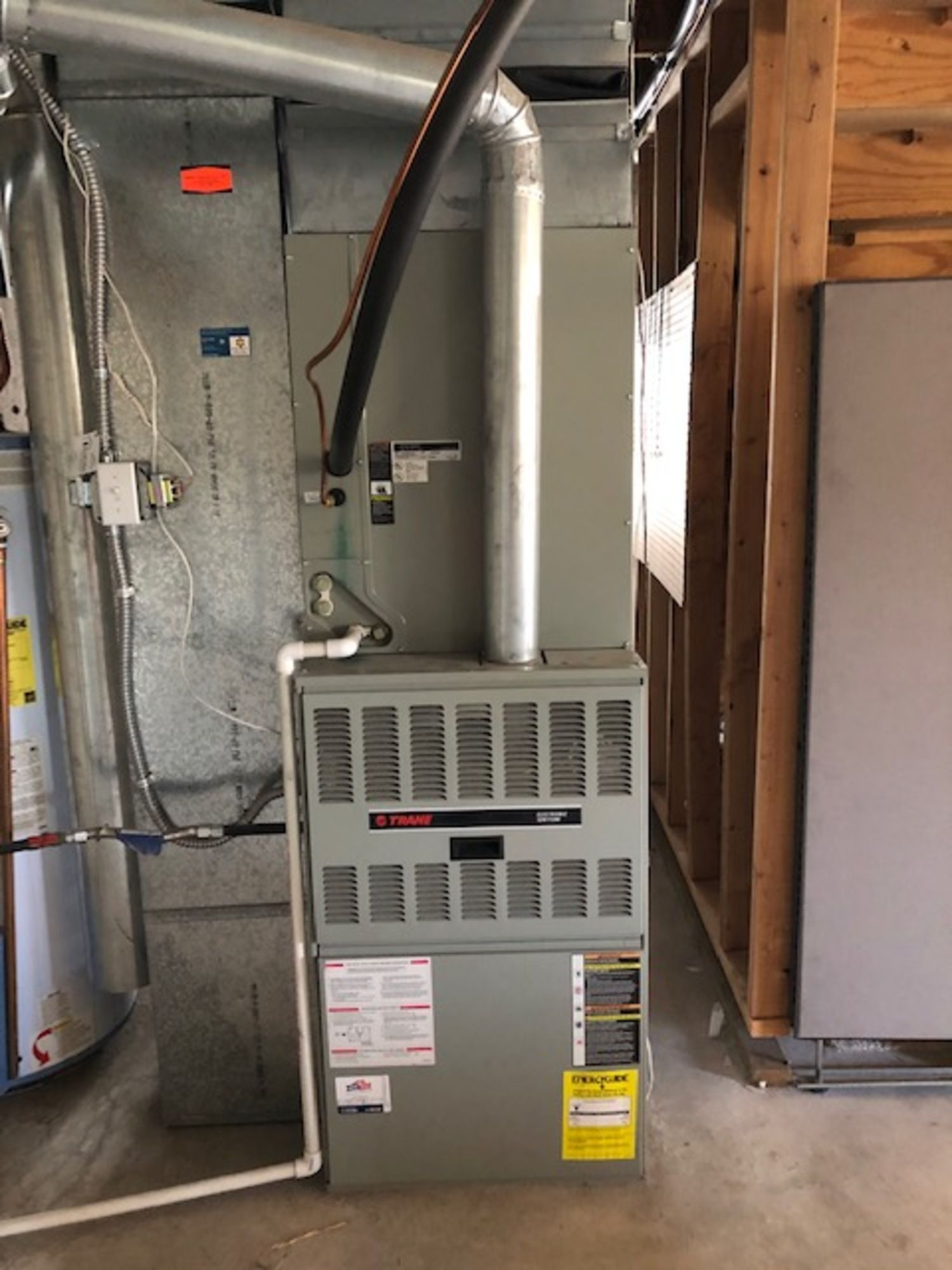 A furnace is sitting in a room next to a water heater.