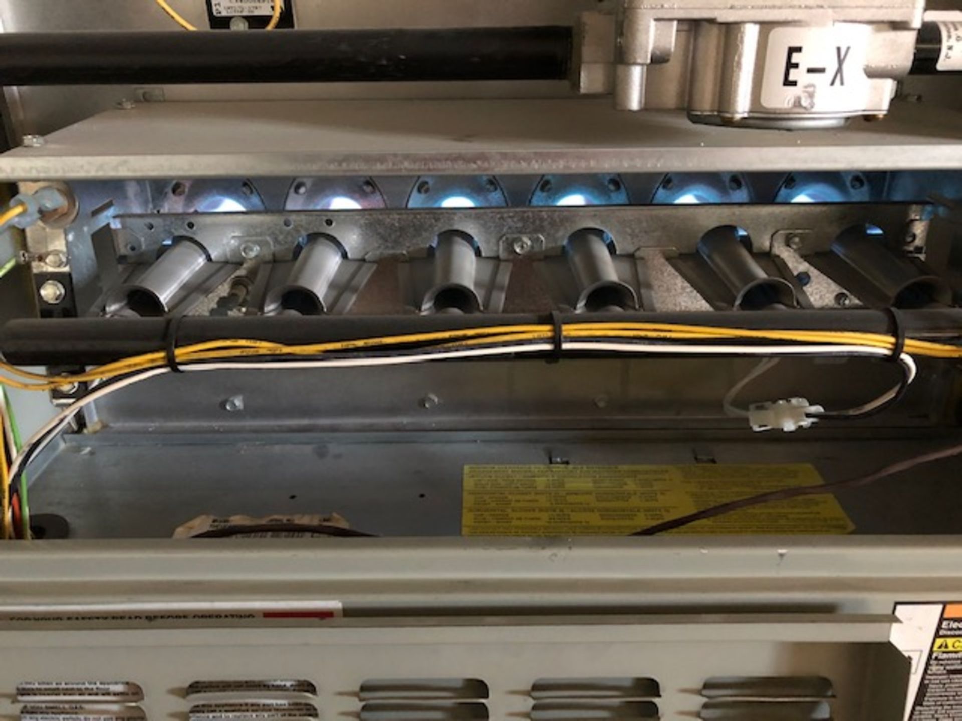 A close up of the inside of a stove with a burner and wires.