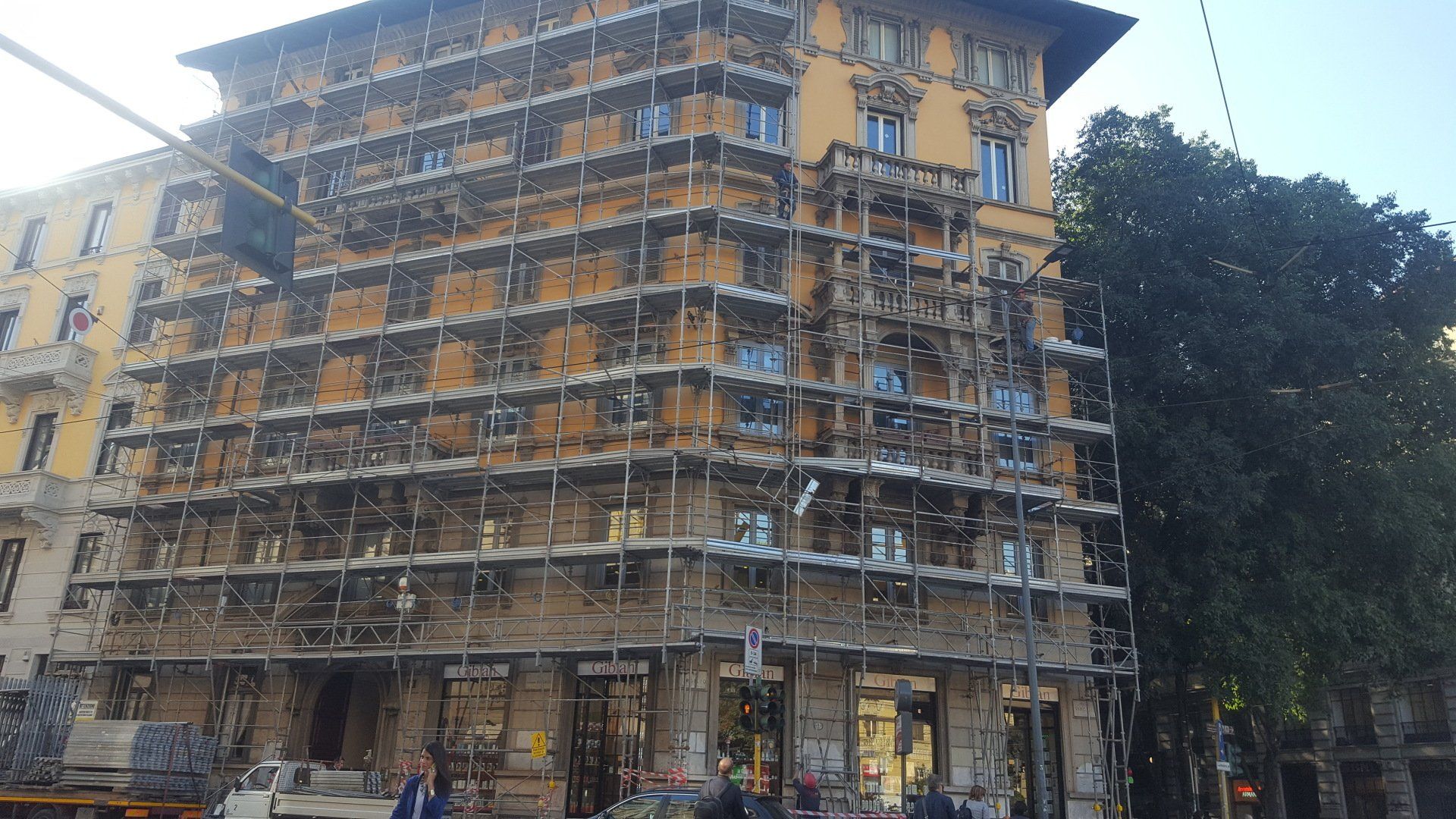 Edificio in fase di ristrutturazione, coperto da impalcature, vista a livello della strada.
