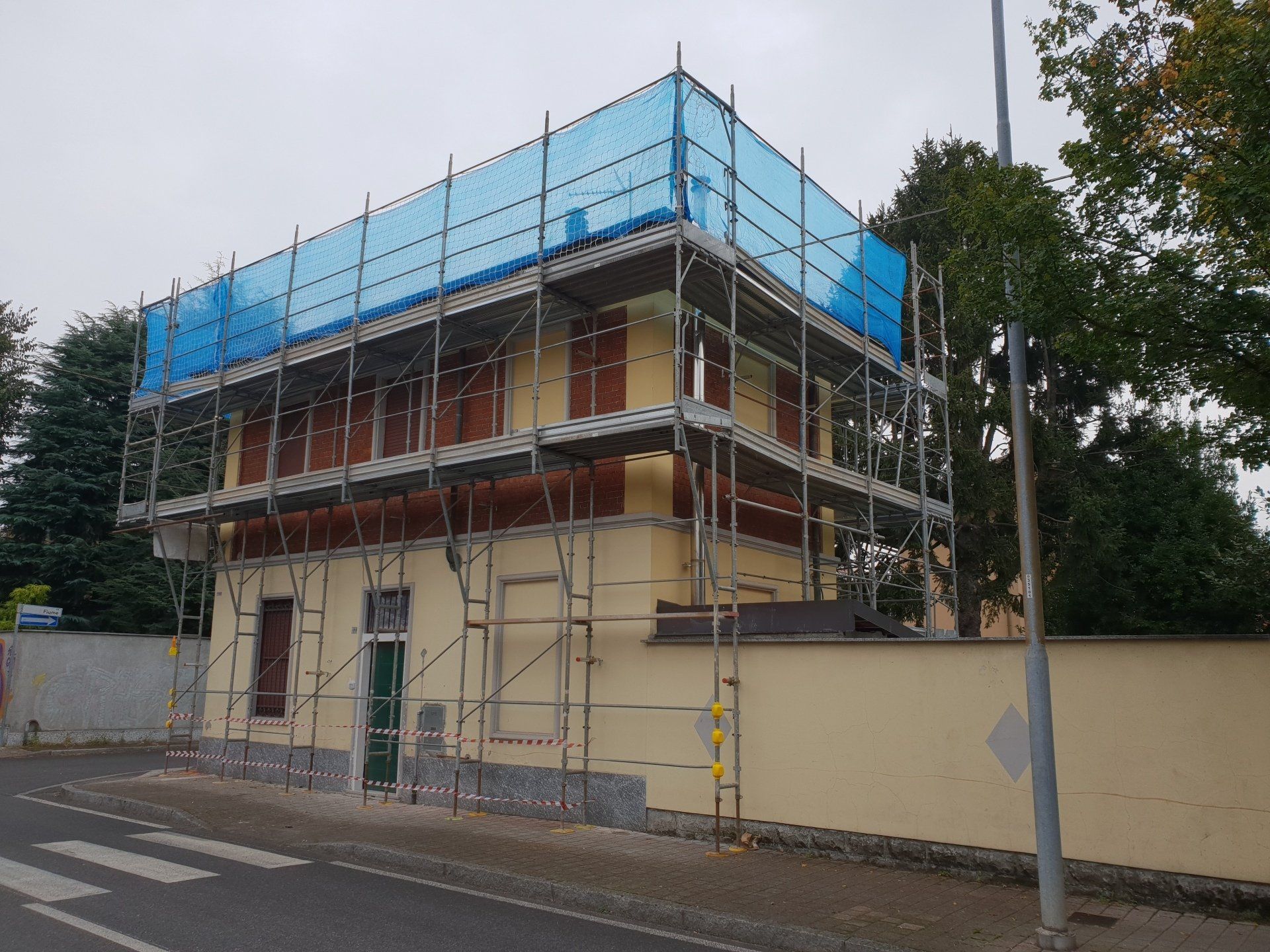 Edificio in fase di ristrutturazione con impalcature e reti blu.