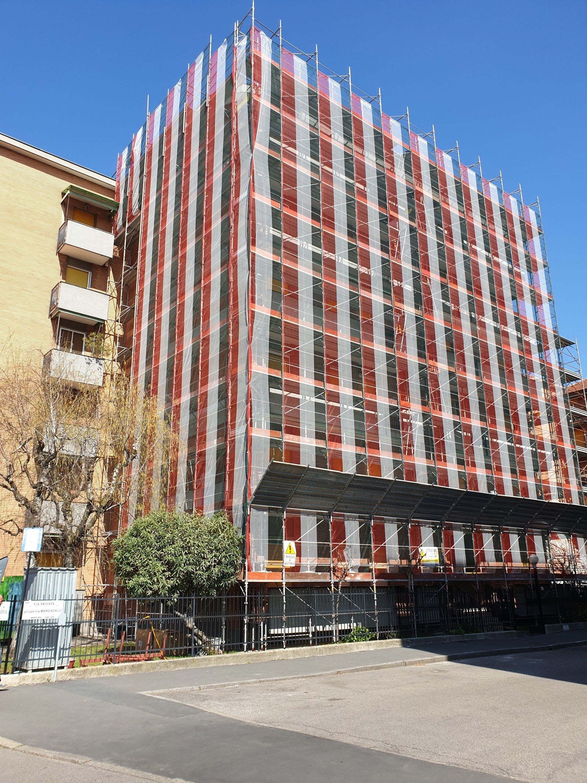Edificio in fase di ristrutturazione, coperto da impalcature e reti di protezione.