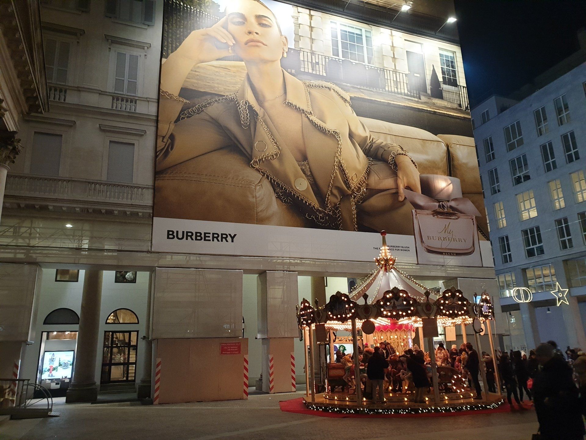 Pubblicità Burberry su un edificio, con una giostra di fronte.
