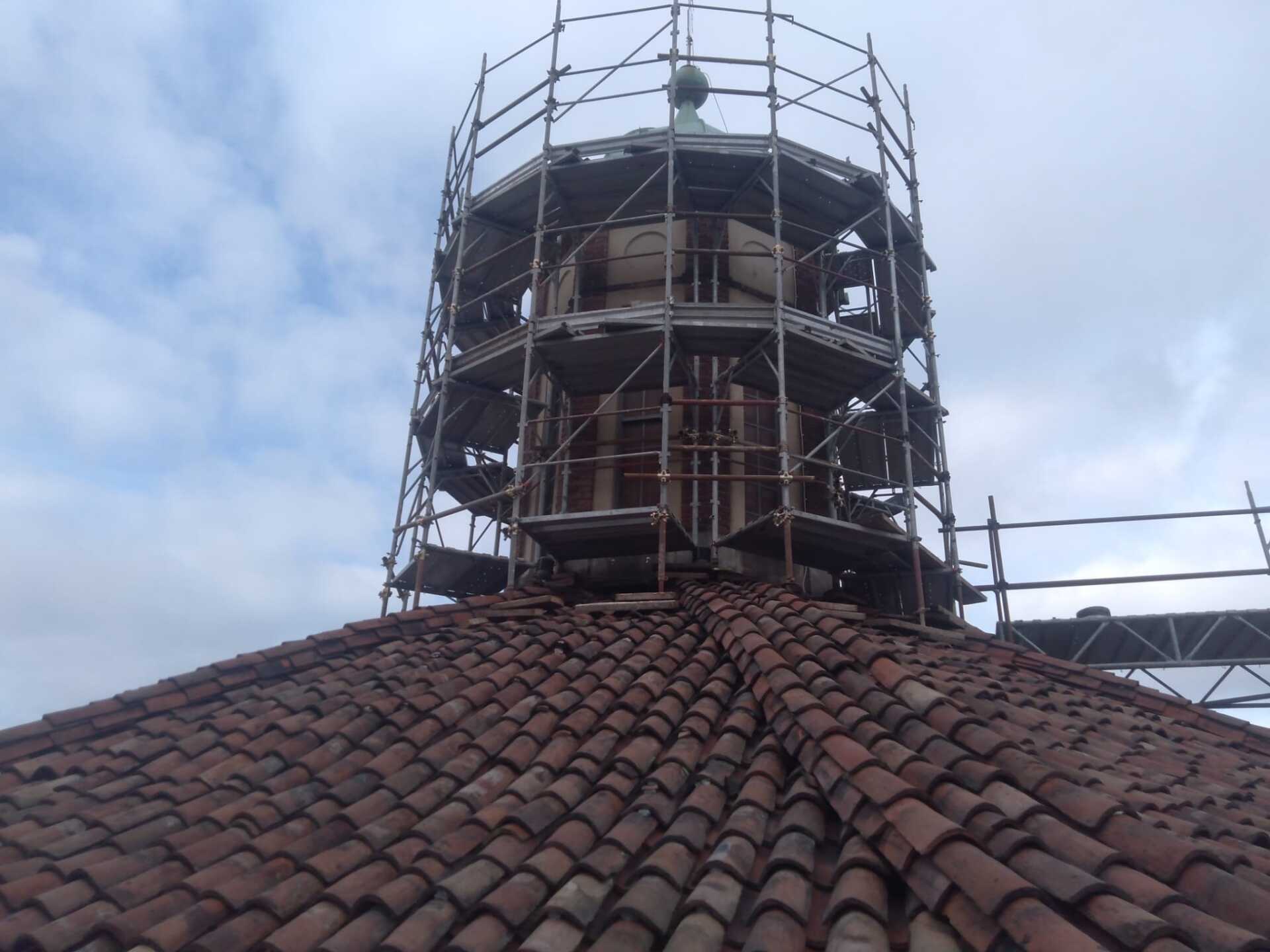 Un tetto a cupola con impalcature attorno a una struttura, sotto un cielo nuvoloso.