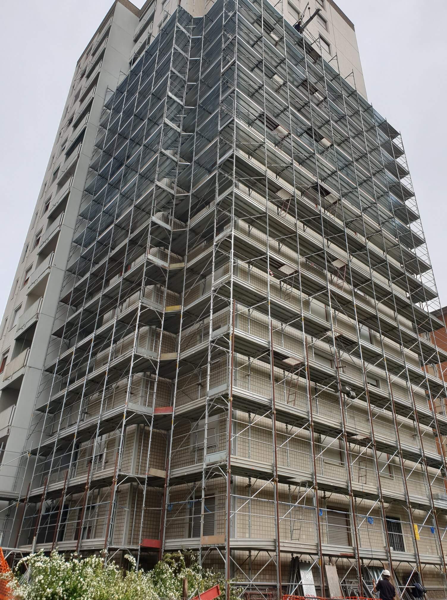 Edificio di grandi dimensioni in costruzione con ampie impalcature che ricoprono la facciata.