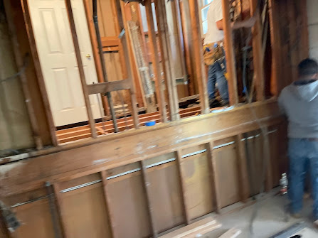 A man is standing in a room with wooden walls.