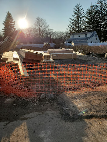 A pile of wood is sitting on top of an orange fence.