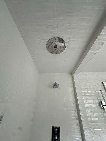 A shower head is hanging from the ceiling of a bathroom.