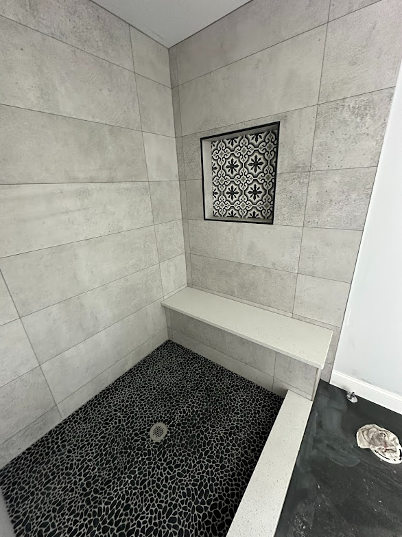 A bathroom with a walk in shower and a bench.