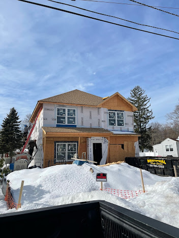 A house is being built in the snow next to a truck.