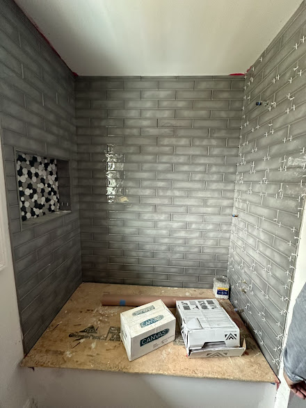 A bathroom with a brick wall and boxes on the floor.