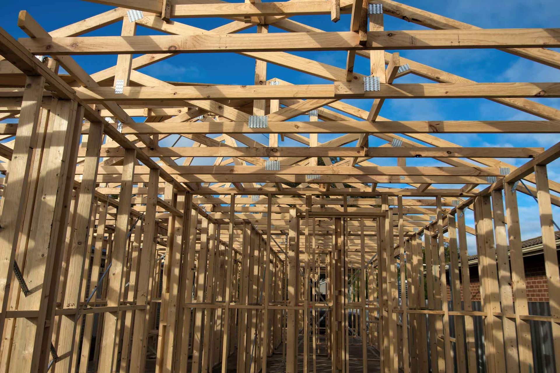 A house is being built with wooden beams and a blue sky in the background.