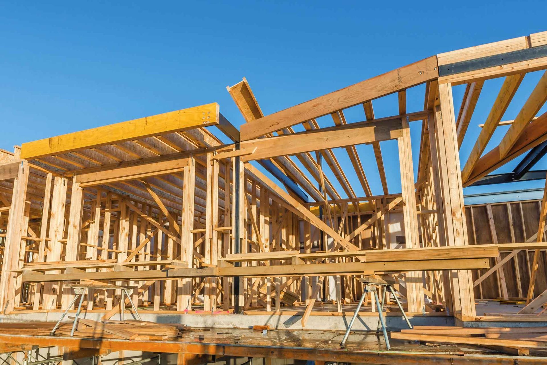 A house is being built with wooden beams and a blue sky in the background.