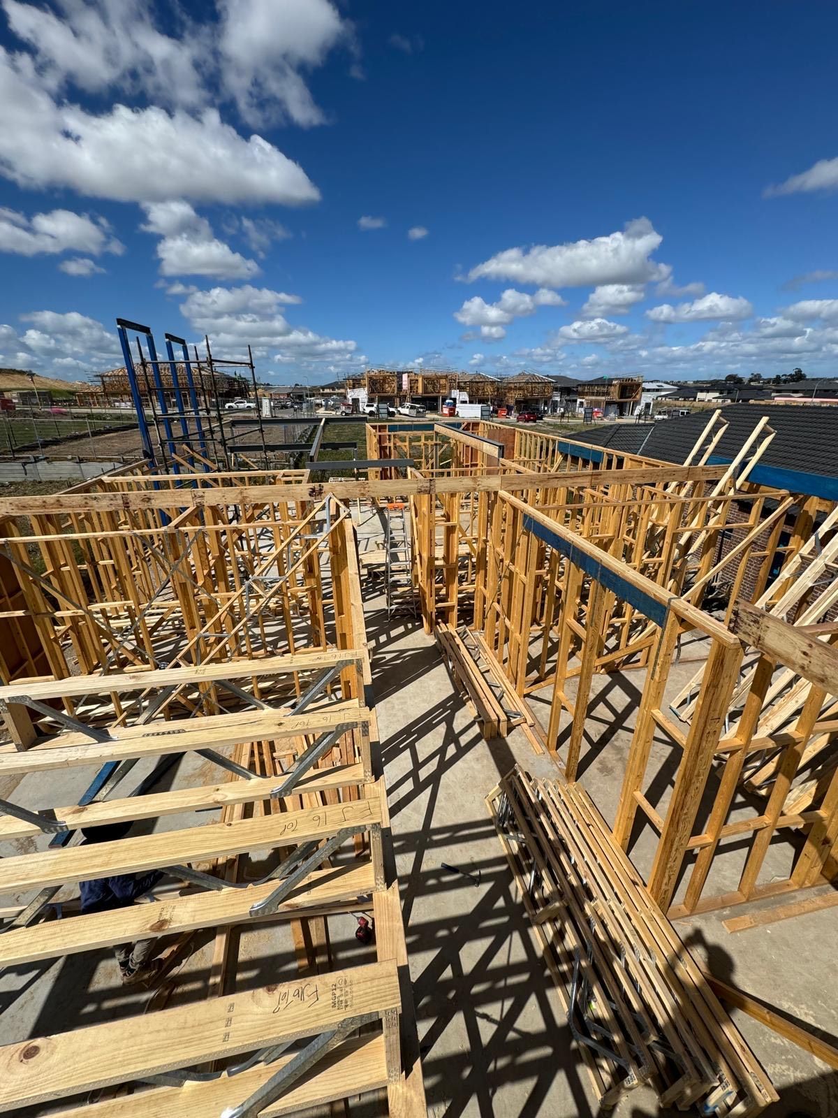 Wooden framework of a building under construction against a blue sky with clouds.
