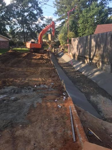 A large orange excavator is working on a concrete driveway.