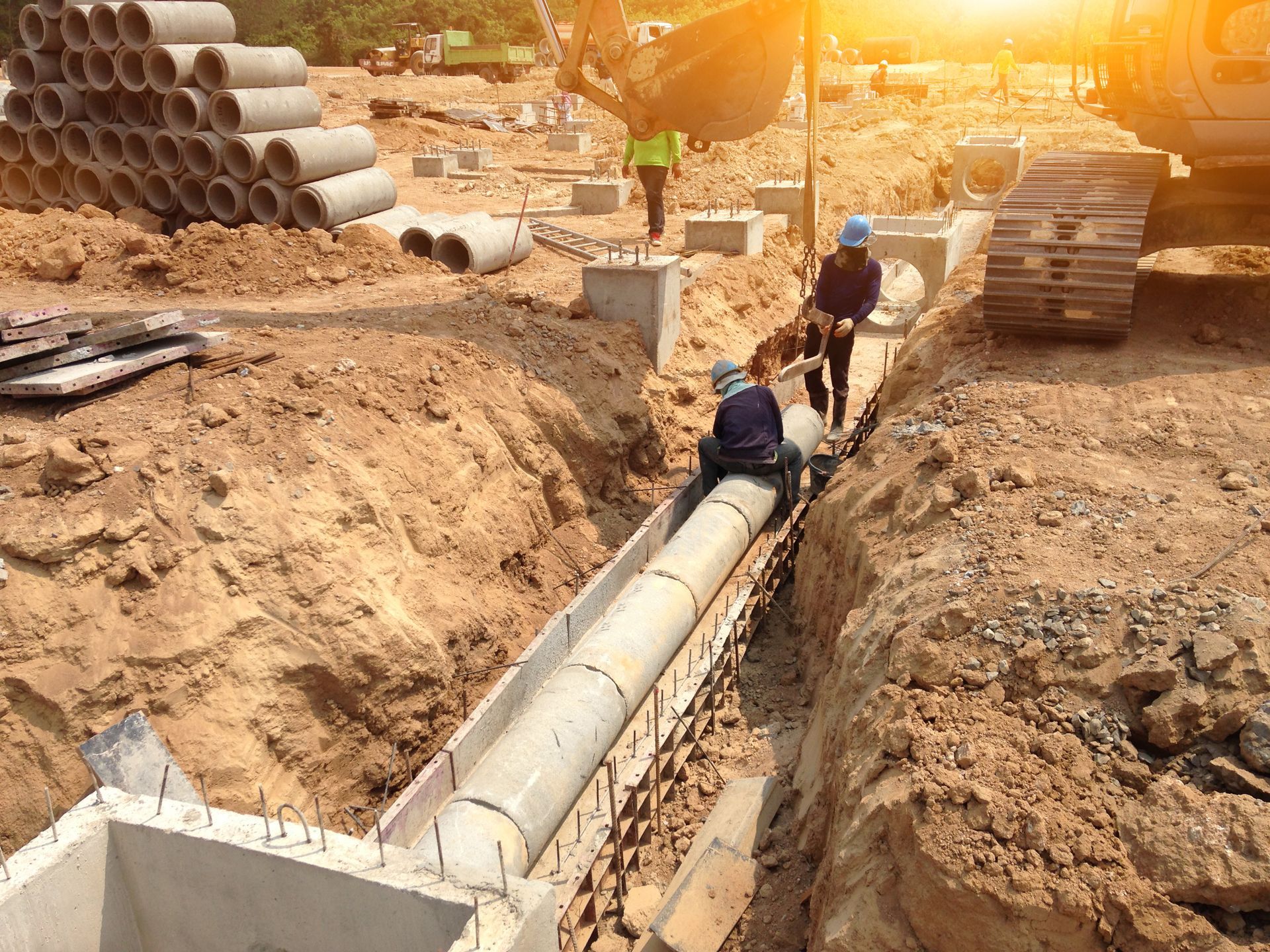 A group of construction workers are working on a pipe in the dirt.