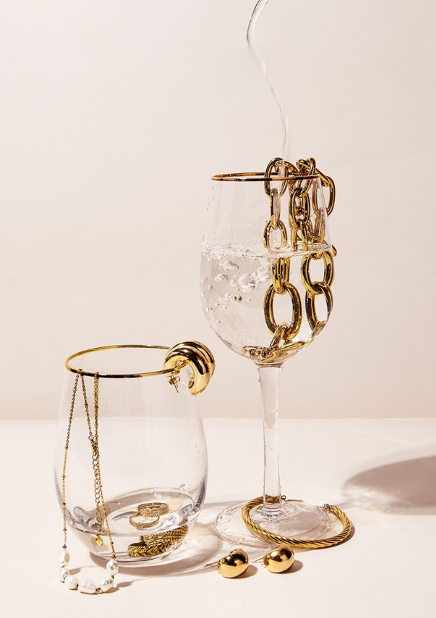 Een wijnglas gevuld met water en sieraden op een tafel.