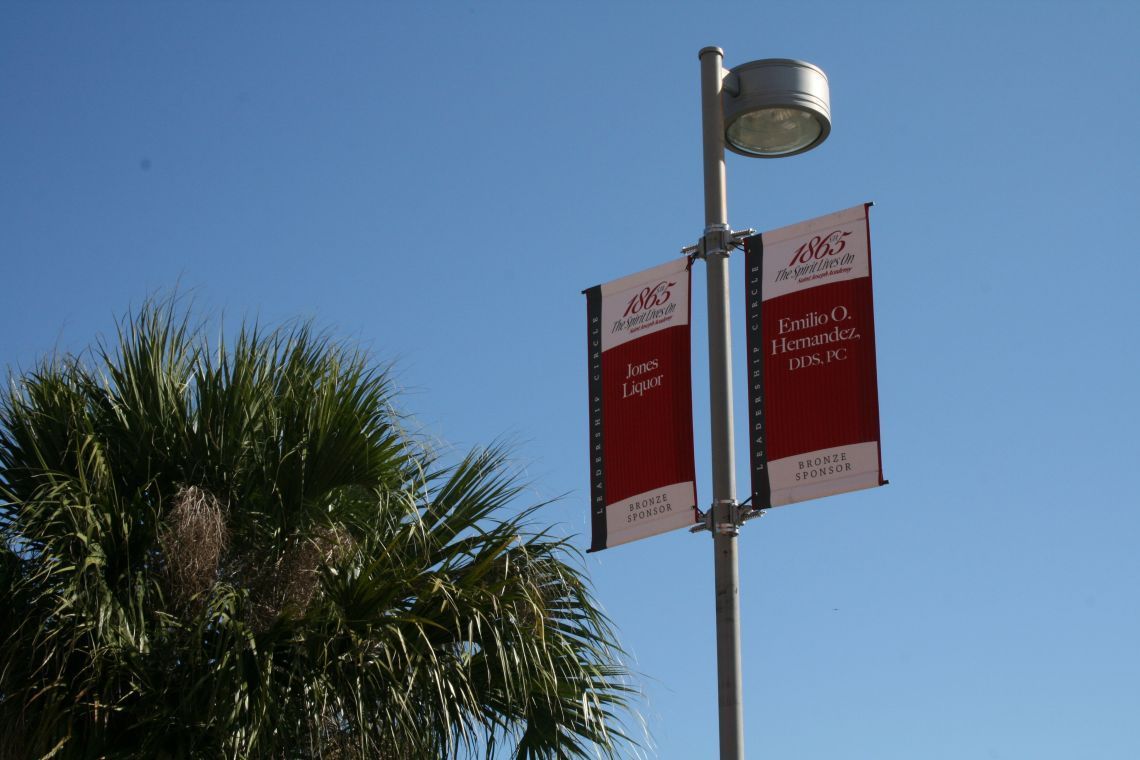 A street light with two banners hanging from it one of which says 