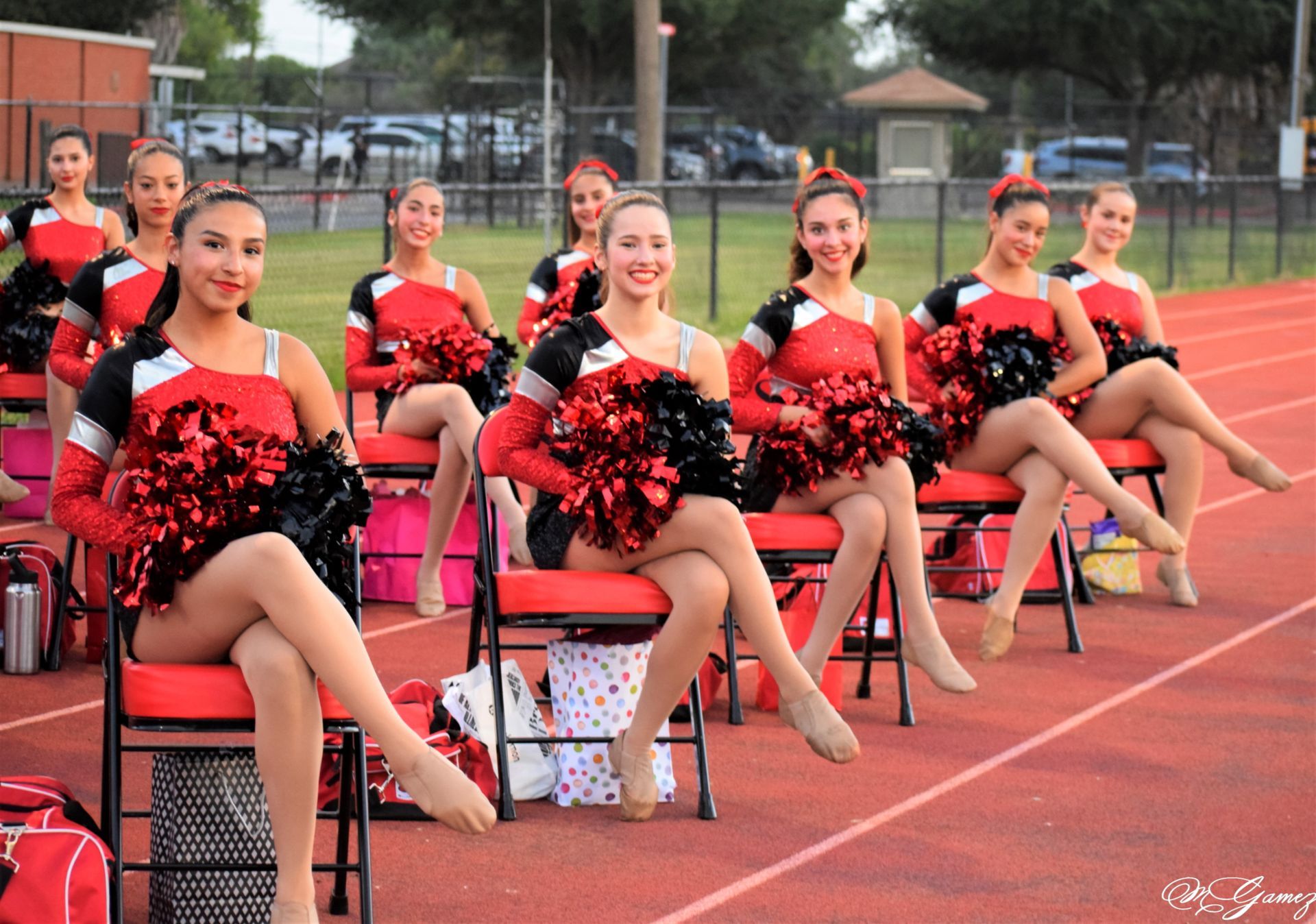 A group of cheerleaders are sitting on chairs on a track