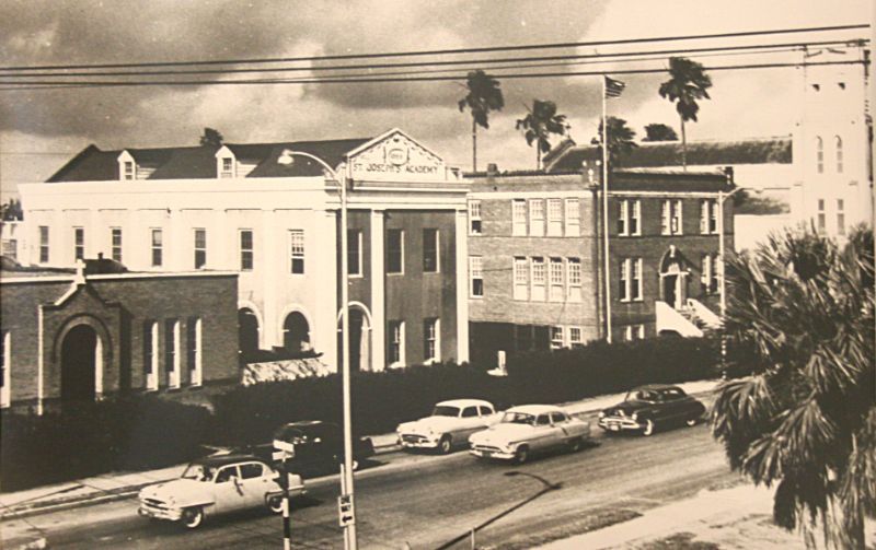 A black and white photo of cars parked in front of a large building