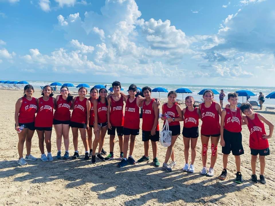 A group of young people are posing for a picture on the beach.