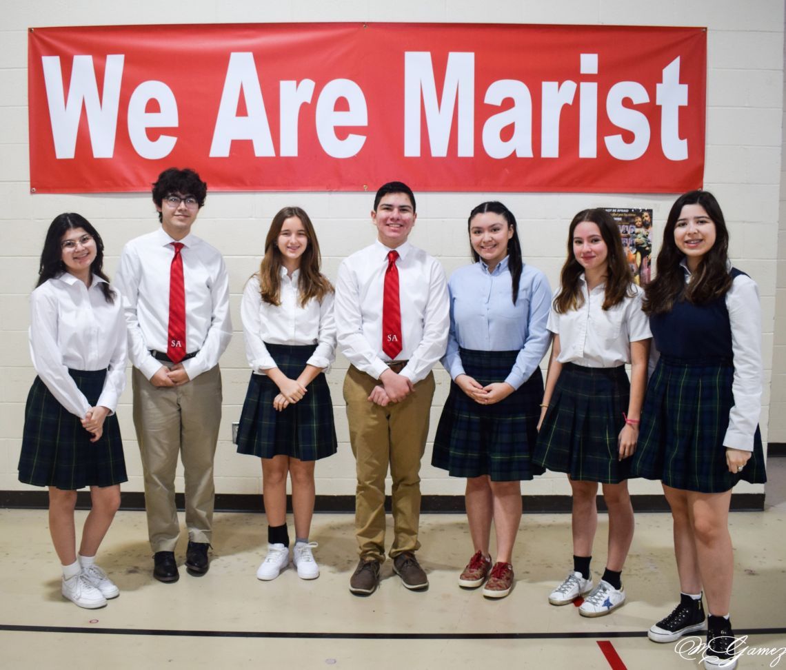 A group of people standing in front of a sign that says we are marist