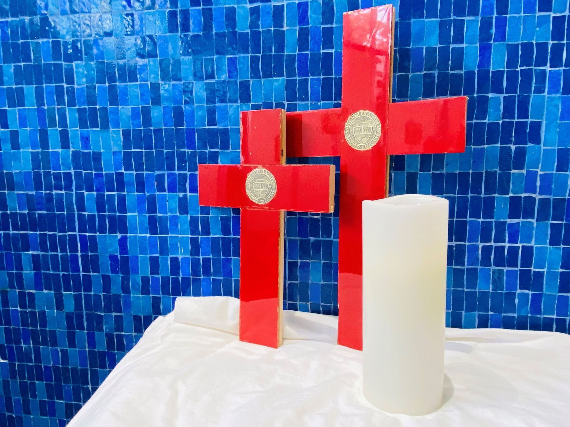 Two red crosses and two white candles on a table