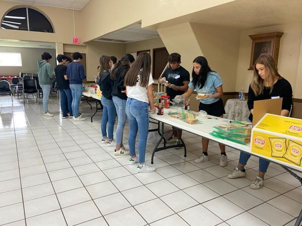 A group of people are standing around a table eating food.