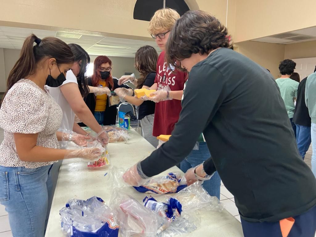 A group of people are gathered around a table and one of them is wearing a shirt that says lee jeans