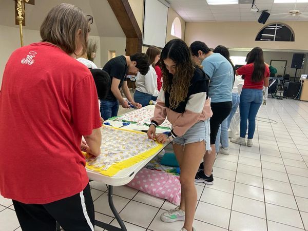 A group of people are working on a quilt at a table.
