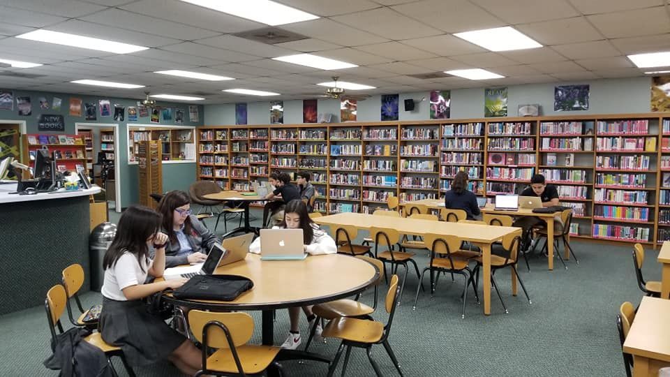 A group of people are sitting at tables in a library