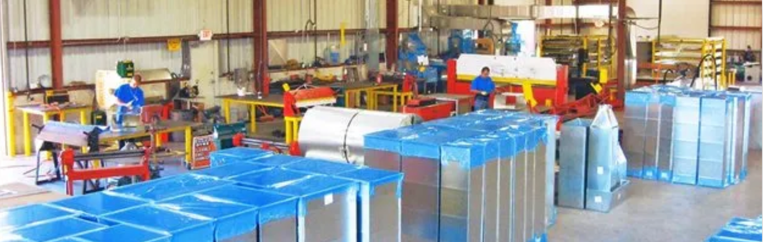 Workers inside a manufacturing warehouse assembling and packaging metal ductwork components.