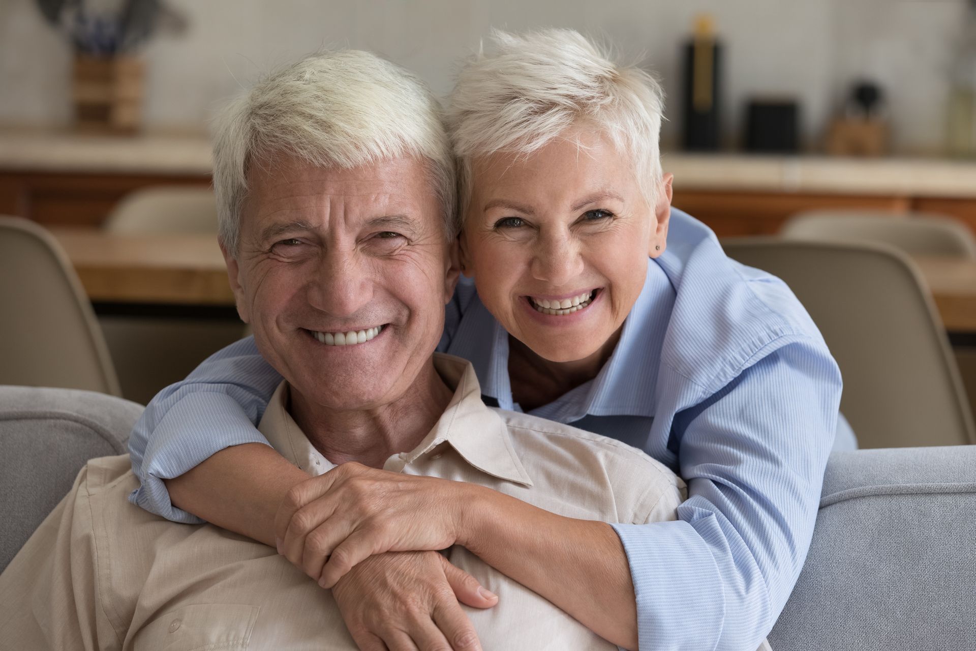 a woman is hugging an older man on a couch