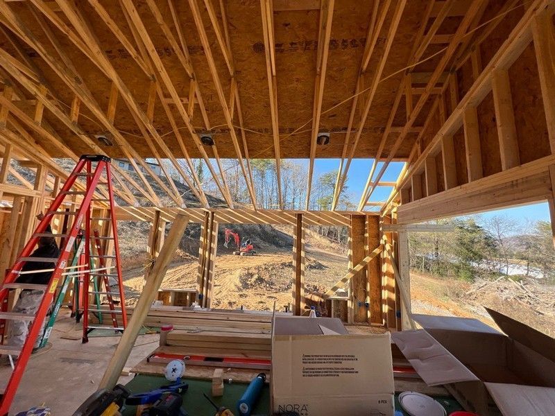 The inside of a house under construction with a ladder and boxes on the floor.