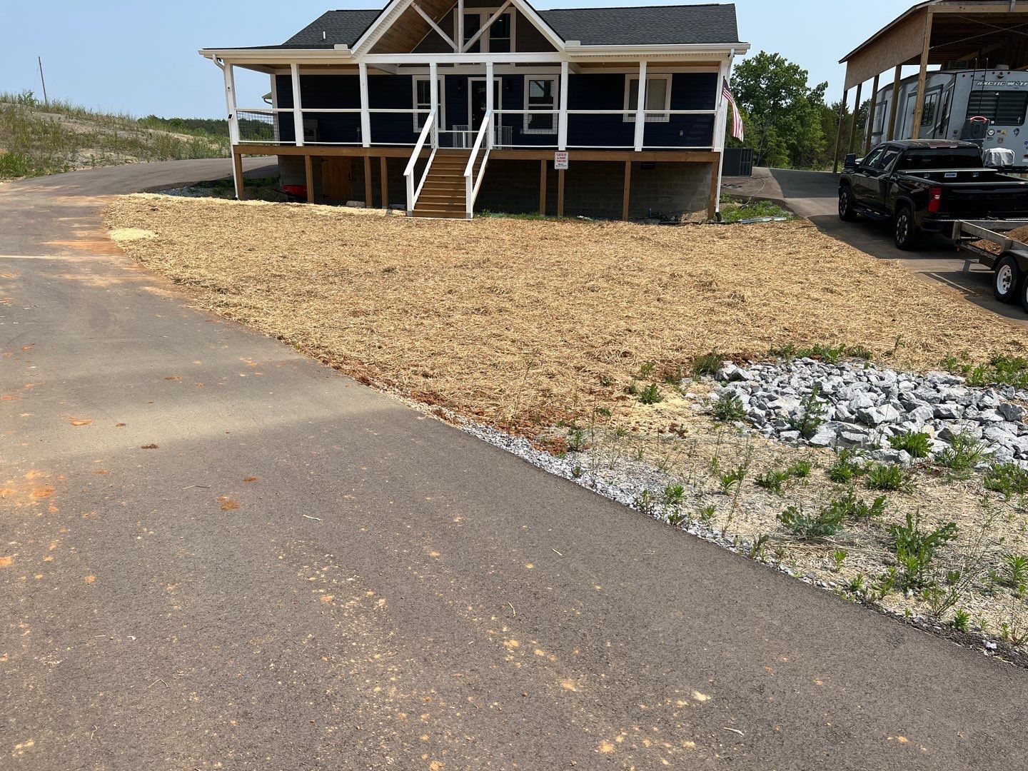 A house is sitting on top of a dirt hill next to a road