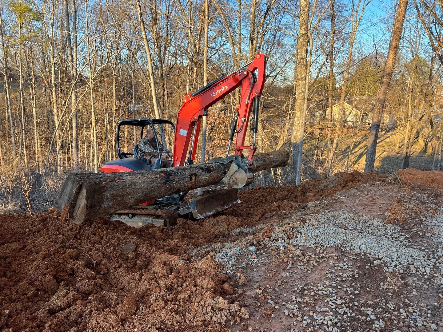 A red and black excavator is digging a hole in the dirt.
